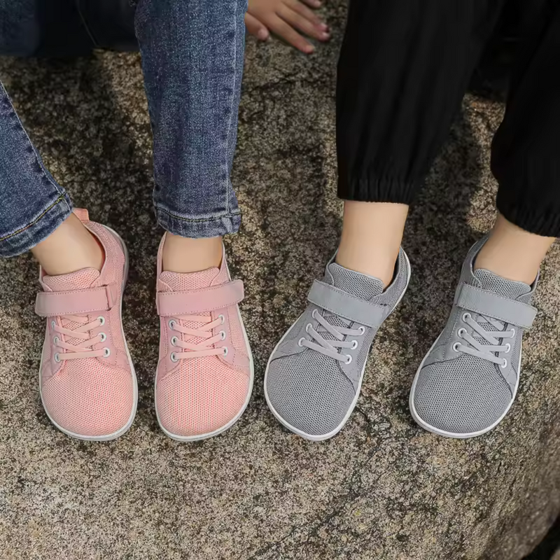 Laden Sie das Bild in Galerie -Viewer, Zwei Paar Sneaker auf Felsen, rosa und grau, getragen von Personen in Jeans und schwarzen Hosen. Bequeme Freizeitschuhe, modisch und lässig.
