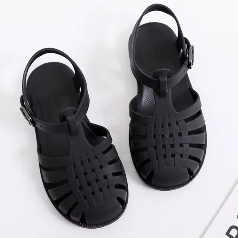 Laden Sie das Bild in Galerie -Viewer, Schwarze Sandalen aus Kunststoff mit geflochtenem Design und verstellbarem Riemen auf weißem Hintergrund. Ideal für Sommermode und Strand.
