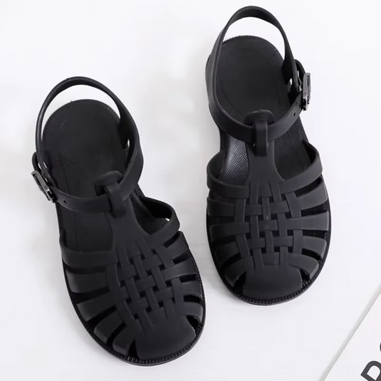 Schwarze Sandalen aus Kunststoff mit geflochtenem Design und verstellbarem Riemen auf weißem Hintergrund. Ideal für Sommermode und Strand.