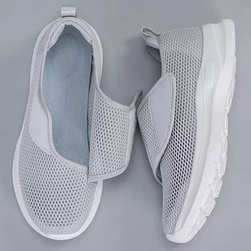 Laden Sie das Bild in Galerie -Viewer, Graue, atmungsaktive Mesh-Sneaker mit Klettverschluss auf grauem Hintergrund. Bequeme, leichte Sportschuhe für Damen und Herren.
