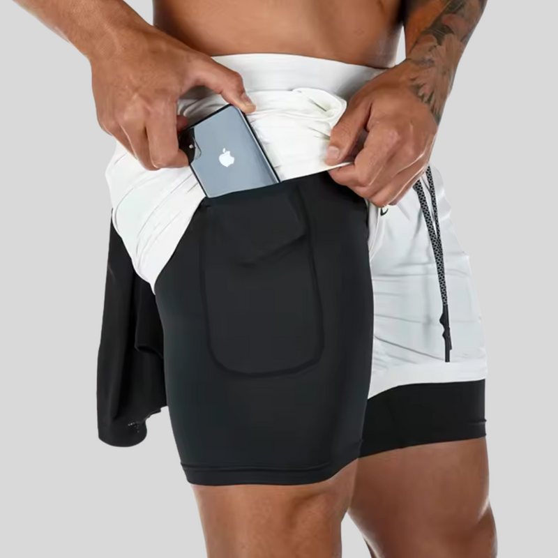 Laden Sie das Bild in Galerie -Viewer, Mann in Sportshorts mit integriertem Handytasche, steckt Smartphone ein. Fitnessmode, praktische Sportbekleidung, funktionale Shorts für Herren.
