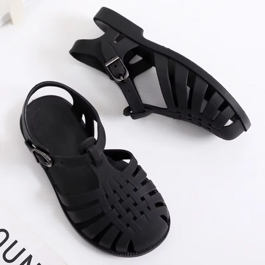 Schwarze Sandalen aus Kunststoff mit Riemchen-Design und Schnallenverschluss auf weißem Hintergrund. Ideal für Sommermode und Freizeitkleidung.