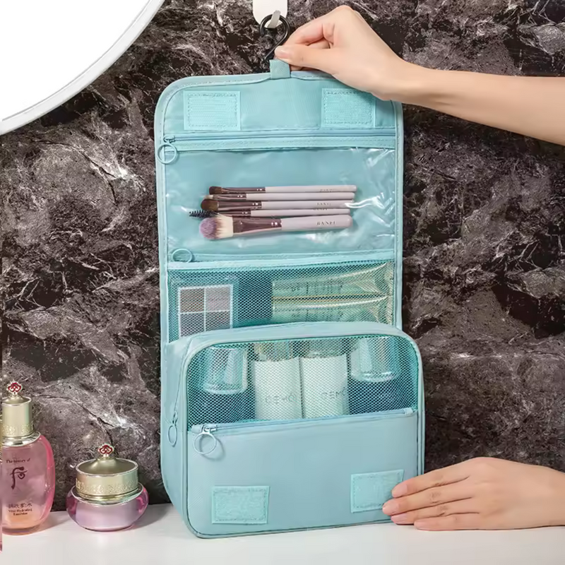 Laden Sie das Bild in Galerie -Viewer, Hängender Kulturbeutel in Blau mit mehreren Fächern, gefüllt mit Make-up-Pinseln und Kosmetikflaschen, ideal für Reisen und Badezimmerorganisation.

