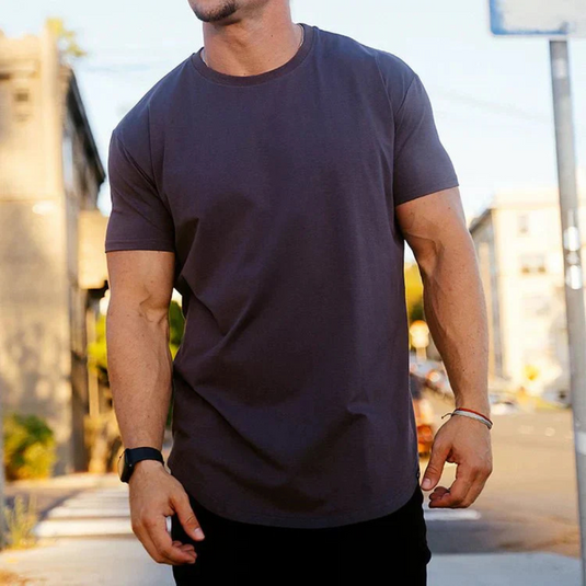 Mann in dunkelgrauem T-Shirt auf städtischer Straße, lässiger Stil, Sommermode, modernes Outfit, urbaner Hintergrund, Tageslicht.
