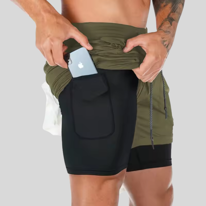 Laden Sie das Bild in Galerie -Viewer, Mann in Sportshorts mit Smartphone in der Tasche, Fitnessmode, bequeme Sportbekleidung, funktionale Taschen, ideal für Training und Outdoor-Aktivitäten.
