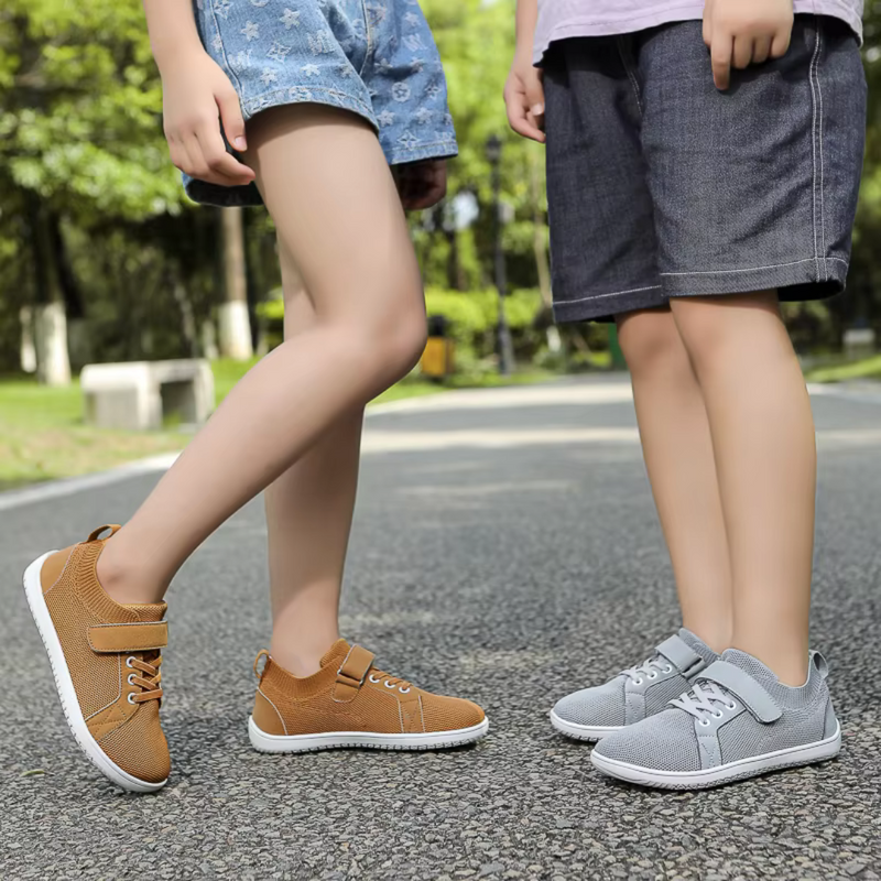 Laden Sie das Bild in Galerie -Viewer, Zwei Kinder in Freizeitkleidung tragen bequeme, modische Sneaker auf einer Straße im Freien. Schuhe in Braun und Grau, ideal für den Alltag.
