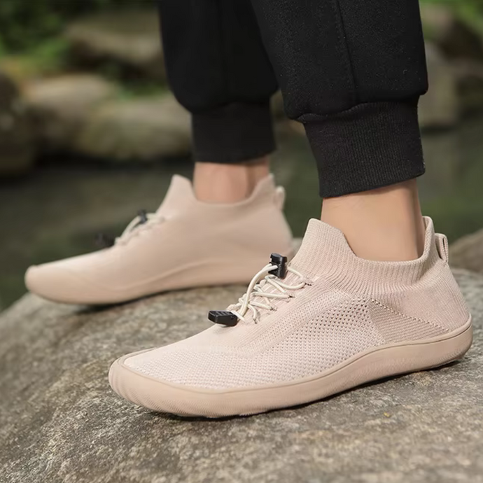 Beige Sneaker auf Felsen, atmungsaktives Strickmaterial, sportlich, ideal für Outdoor-Aktivitäten, modisch, bequem, Herrenmode, Freizeitschuhe.