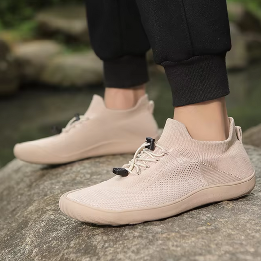 Beige Sneaker auf Felsen, atmungsaktives Strickmaterial, sportlich, ideal für Outdoor-Aktivitäten, modisch, bequem, Herrenmode, Freizeitschuhe.