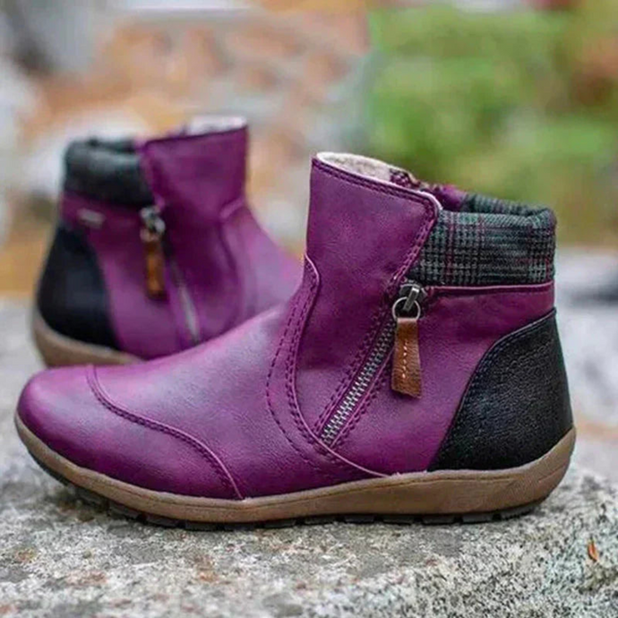 Lila Damenstiefeletten mit Reißverschluss, schwarzem Fersenbereich und kariertem Schaft. Bequeme, modische Herbstschuhe auf Steinuntergrund.