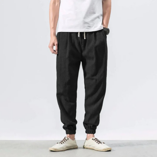 Mann trägt schwarze Jogginghose und weiße Sneakers, lässiger Stil, Mode für Herren, bequeme Freizeitkleidung, modernes Design.