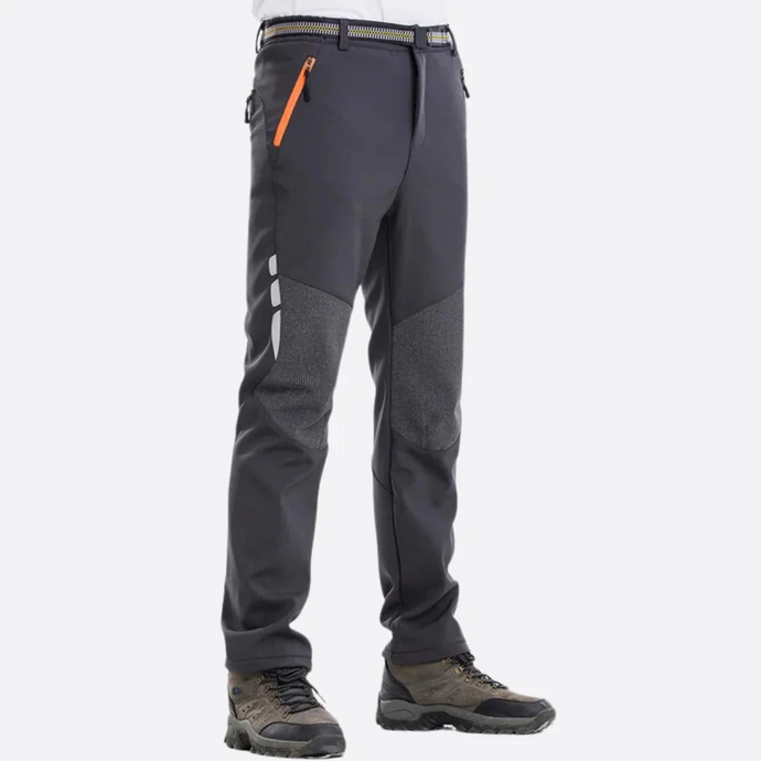 Dunkelgraue Outdoor-Hose mit orangefarbenem Reißverschluss, verstärkten Knien und Wanderschuhen. Ideal für Trekking und Outdoor-Aktivitäten.