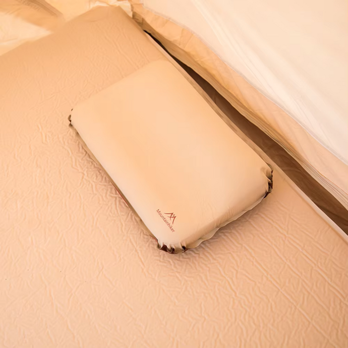 Beiges, rechteckiges Kissen auf einem Bett in einem Zelt, ideal für Camping und Outdoor-Abenteuer. Komfortables Schlafzubehör für Reisen.