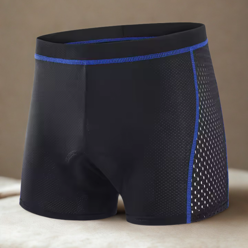 Laden Sie das Bild in Galerie -Viewer, Schwarze Herren-Boxershorts mit blauen Nähten und atmungsaktiven Mesh-Seiten, ideal für Sport und Alltag, auf beigem Hintergrund.
