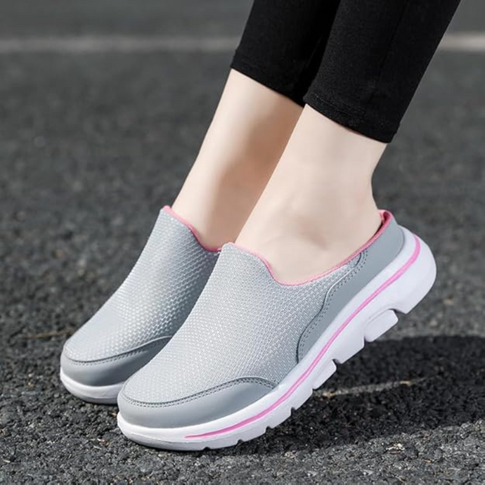 Graue Damen-Sneaker mit rosa Akzenten auf Asphalt. Bequeme, atmungsaktive Freizeitschuhe, ideal für Spaziergänge und Alltag.