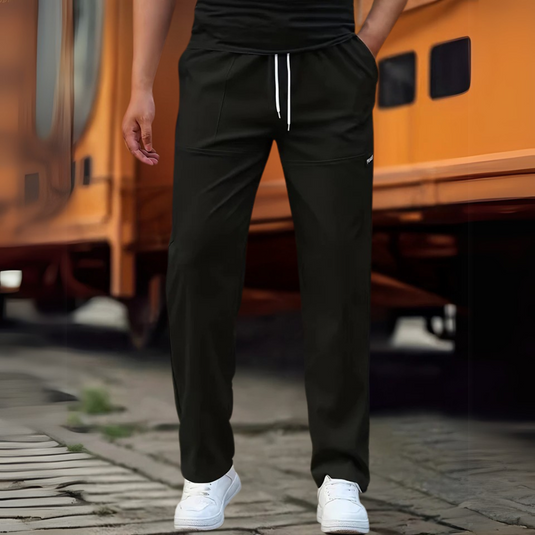 Schwarze Jogginghose für Herren, lässig und bequem, mit weißem Kordelzug, kombiniert mit weißen Sneakers. Ideal für Freizeit und Sport.