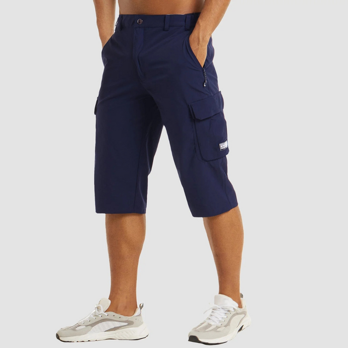 Dunkelblaue Cargo-Bermudashorts für Herren, knielang, mit Seitentaschen. Kombiniert mit weißen Sneakers. Ideal für Sommermode und Freizeitkleidung.