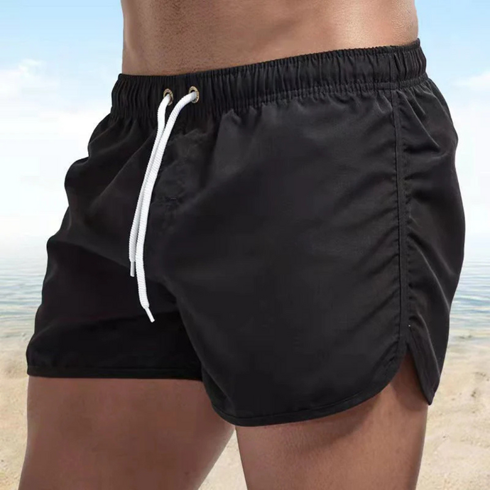 Schwarze Herren-Badeshorts am Strand, elastischer Bund, weiße Kordel, Sommermode, ideal für Strandurlaub und Schwimmen.