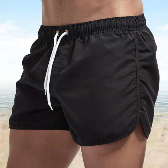 Schwarze Herren-Badeshorts am Strand, elastischer Bund, weiße Kordel, Sommermode, ideal für Strandurlaub und Schwimmen.