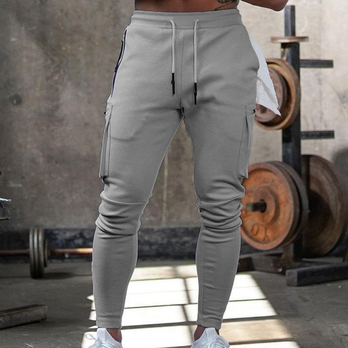 Graue Jogginghose für Herren im Fitnessstudio, mit Kordelzug und Seitentaschen, ideal für Sport und Freizeit. Bequeme Sportbekleidung.
