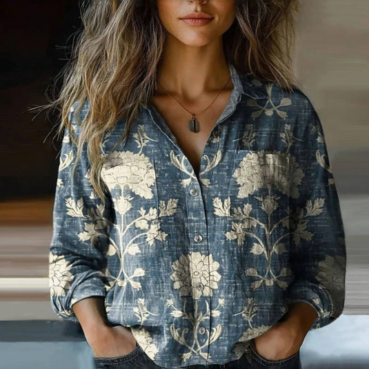 Frau trägt blaues Hemd mit floralem Muster, lässiger Stil, lange Ärmel, V-Ausschnitt, modisches Design, ideal für Freizeitmode und Herbsttrends.