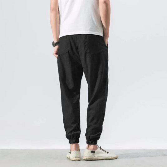 Rückansicht einer Person in schwarzer Jogginghose und weißem T-Shirt, lässiger Stil, weiße Sneaker, minimalistische Mode, Freizeitkleidung.
