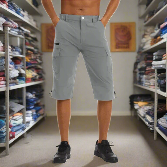 Ein Mann trägt graue Cargo-Shorts in einem gut sortierten Bekleidungsgeschäft. Regale voller gefalteter Kleidung im Hintergrund.