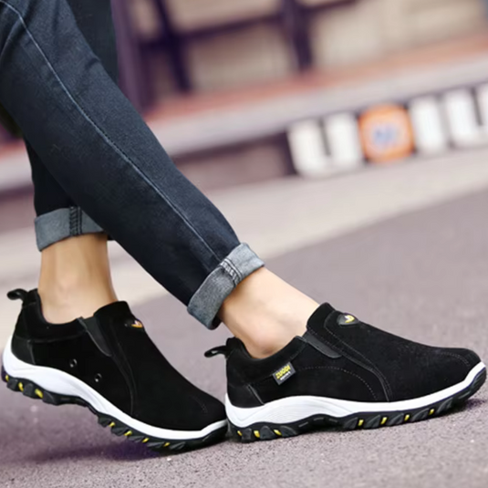Schwarze Herren-Sneaker mit weißer Sohle, getragen von Person in blauen Jeans. Bequeme Freizeitschuhe für Outdoor-Aktivitäten und Alltag.