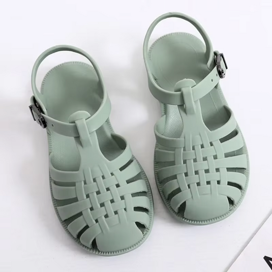 Grüne Sandalen aus Kunststoff mit geflochtenem Design und verstellbarem Riemen auf weißem Hintergrund. Ideal für Sommermode und Strandkleidung.