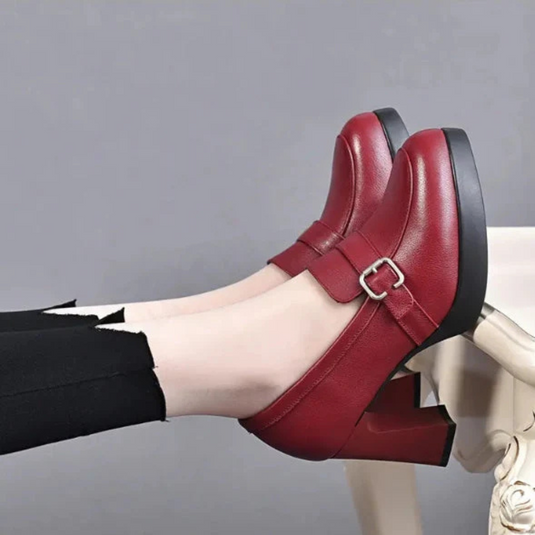 Rote Damen-Loafer mit Blockabsatz und Schnalle, getragen mit schwarzer Hose. Modische, bequeme Schuhe für Herbst und Winter.