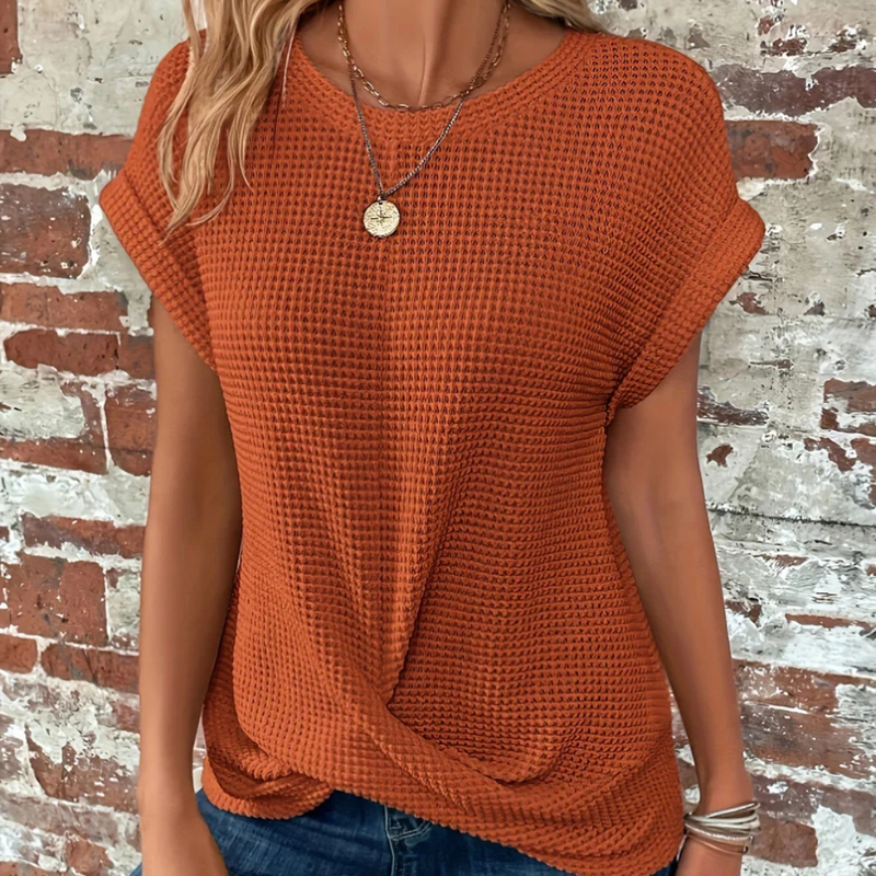 Laden Sie das Bild in Galerie -Viewer, Frau in orangefarbenem Strickpullover vor Backsteinwand, trägt Halskette. Modetrend, lässiger Look, Herbstmode, Damenbekleidung.
