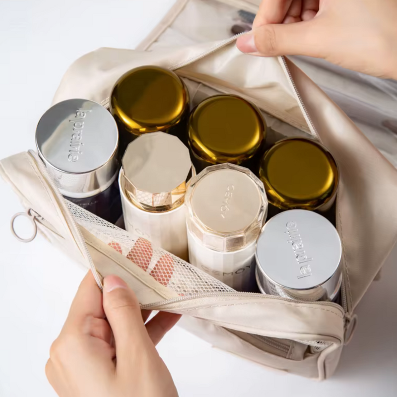 Laden Sie das Bild in Galerie -Viewer, Hände öffnen Kosmetiktasche mit sechs luxuriösen La Prairie Cremedosen, goldene und silberne Deckel, auf weißem Hintergrund. Hochwertige Hautpflege.
