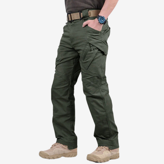 Mann trägt grüne taktische Hose mit mehreren Taschen, beigen Stiefeln und einer Armbanduhr. Outdoor-Bekleidung, funktionale Mode, robuste Hosen.