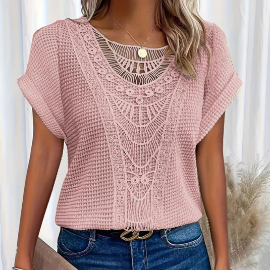 Frau trägt rosa Häkelbluse mit Spitzenmuster, kombiniert mit blauer Jeans. Modetrend, Sommeroutfit, Damenmode, stilvolle Freizeitkleidung.