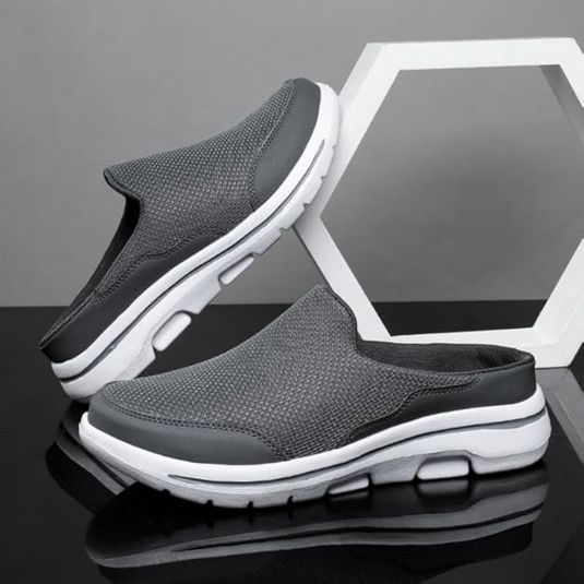 Graue Herren-Sneaker-Slipper mit weißer Sohle, atmungsaktivem Mesh-Obermaterial, auf schwarzem und grauem Hintergrund, modisch und bequem.