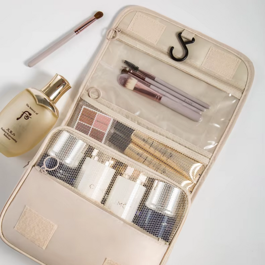 Beige Reise-Kosmetiktasche mit Make-up-Pinseln, Lidschatten, Parfümflasche und Pflegeprodukten. Praktische Aufbewahrung für unterwegs.