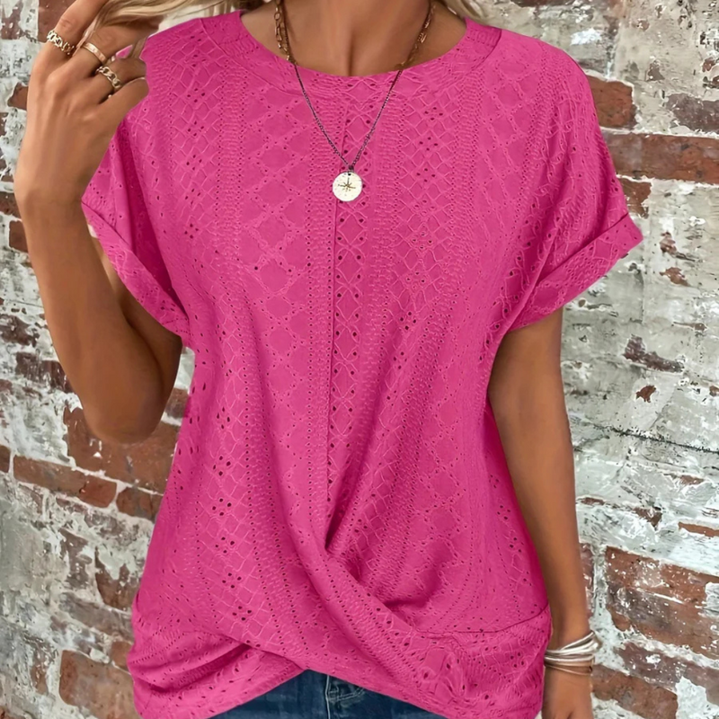 Laden Sie das Bild in Galerie -Viewer, Frau trägt pinkes, gehäkeltes T-Shirt vor Backsteinwand, modisches Sommeroutfit, lässiger Stil, Schmuckaccessoires, trendige Damenmode.
