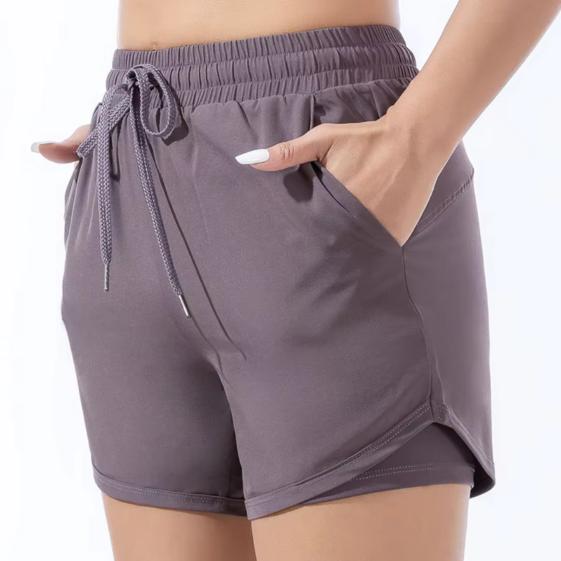 Laden Sie das Bild in Galerie -Viewer, Damen-Sportshorts in Grau mit elastischem Bund und Kordelzug, seitlichen Taschen, ideal für Fitness und Freizeit. Bequeme und stilvolle Sportbekleidung.
