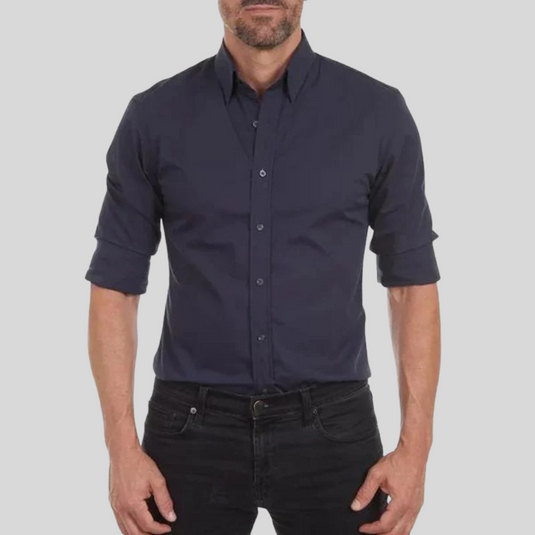 Mann in dunkelblauem Hemd mit hochgekrempelten Ärmeln und schwarzer Hose vor grauem Hintergrund. Elegante Herrenmode, Freizeitlook.