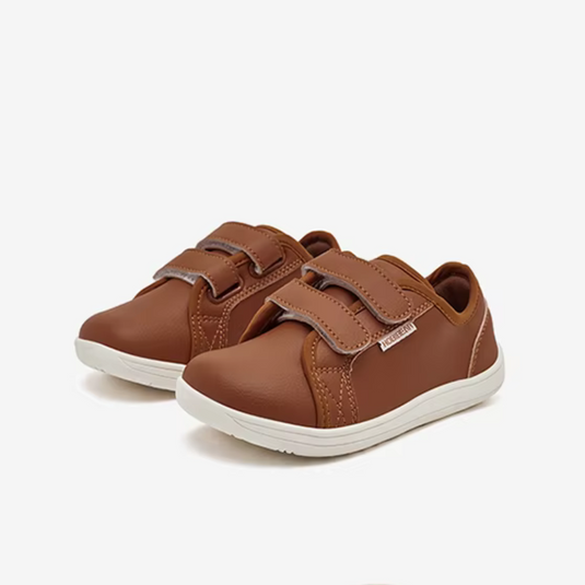 Braune Kinderschuhe mit Klettverschluss, aus Lederimitat, auf weißem Hintergrund. Bequeme, modische Sneaker für Kinder.