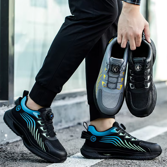 Mann hält zwei Paar modische Sportschuhe, eines in der Hand, eines am Fuß. Schwarze und graue Sneaker mit bunten Akzenten, ideal für Laufen und Freizeit.
