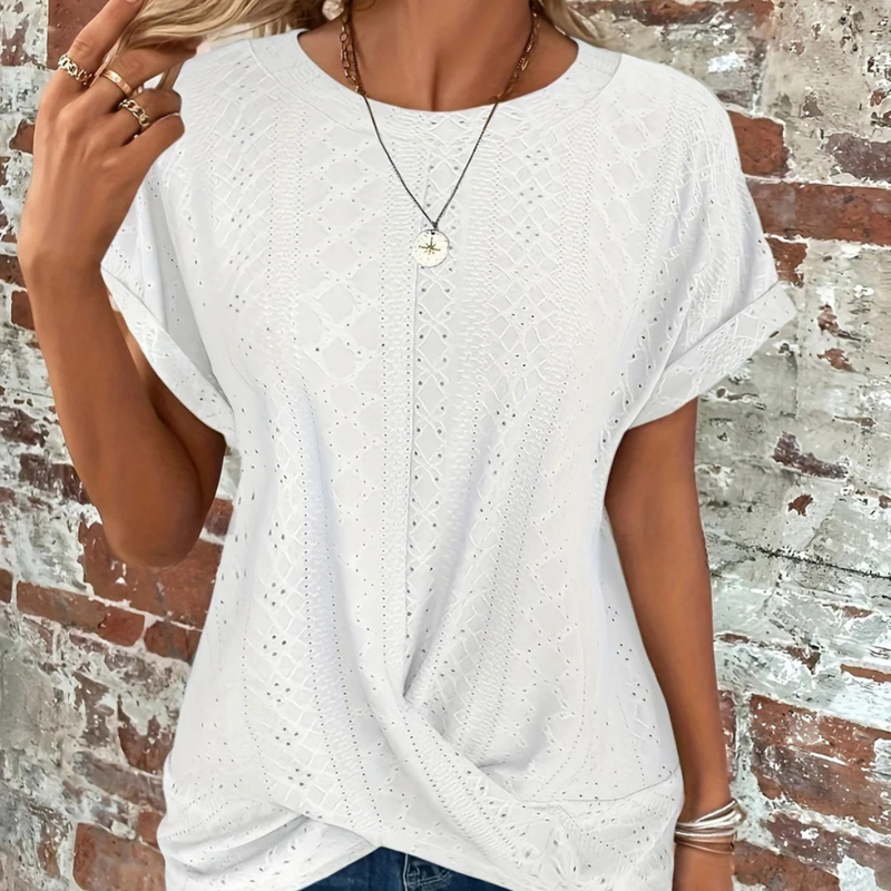 Laden Sie das Bild in Galerie -Viewer, Frau in weißem Spitzen-T-Shirt vor Backsteinwand, trägt Halskette und Ringe. Modetrend, Sommeroutfit, lässiger Stil, Damenmode.

