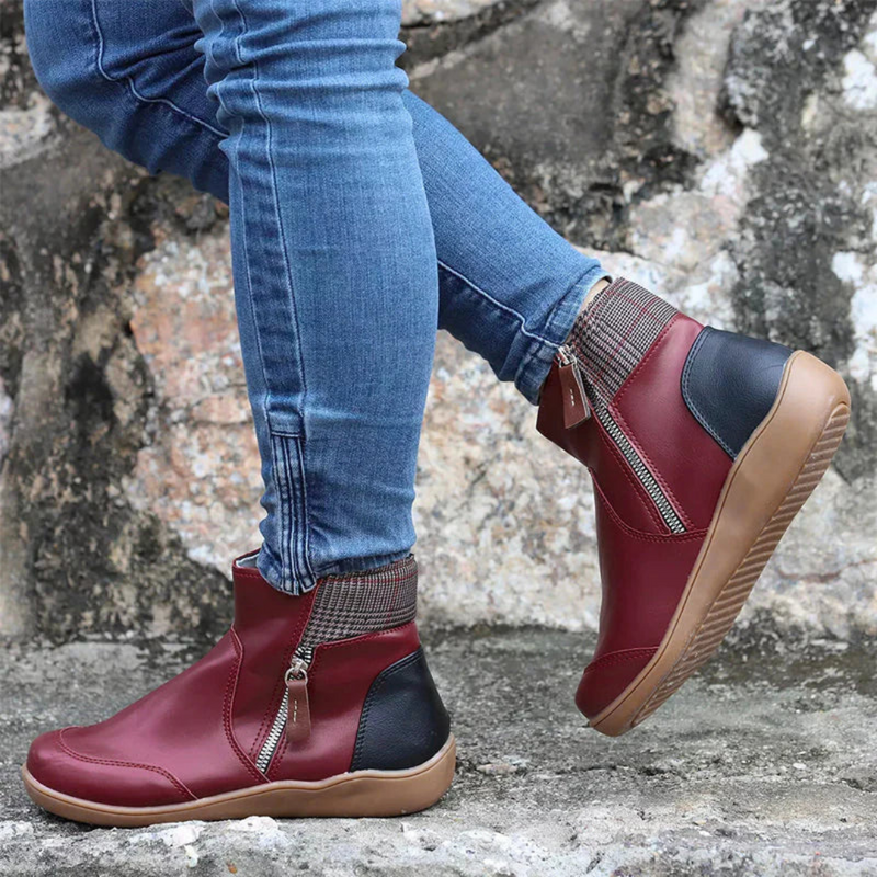 Laden Sie das Bild in Galerie -Viewer, Rote Damenstiefeletten mit Reißverschluss, kombiniert mit blauen Jeans, auf grauem Steinboden. Modische Herbstschuhe, bequem und stilvoll.
