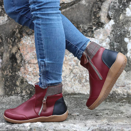 Rote Damenstiefeletten mit Reißverschluss, kombiniert mit blauen Jeans, auf grauem Steinboden. Modische Herbstschuhe, bequem und stilvoll.