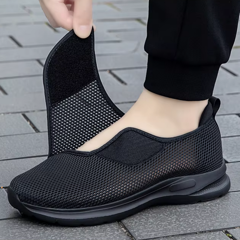 Laden Sie das Bild in Galerie -Viewer, Schwarzer, atmungsaktiver Sneaker mit abnehmbarem Klettverschluss-Oberteil auf grauem Pflaster. Bequeme, modische Schuhe für Damen und Herren.
