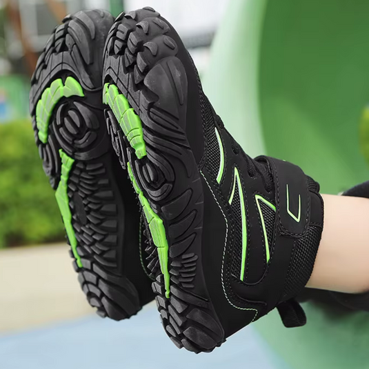 Schwarze Kinderschuhe mit grünen Akzenten und robusten, rutschfesten Sohlen, ideal für Outdoor-Aktivitäten und Abenteuer im Freien.