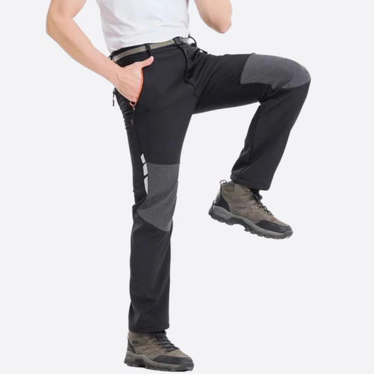 Mann in Outdoor-Hose mit verstärkten Knien, schwarzer Farbe, trägt Wanderschuhe. Ideal für Trekking und Outdoor-Aktivitäten.