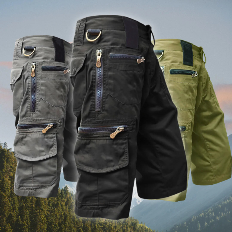 Laden Sie das Bild in Galerie -Viewer, Drei taktische Cargoshorts in Grau, Schwarz und Olivgrün mit Reißverschlusstaschen und D-Ringen, vor Berglandschaft. Ideal für Outdoor-Aktivitäten.
