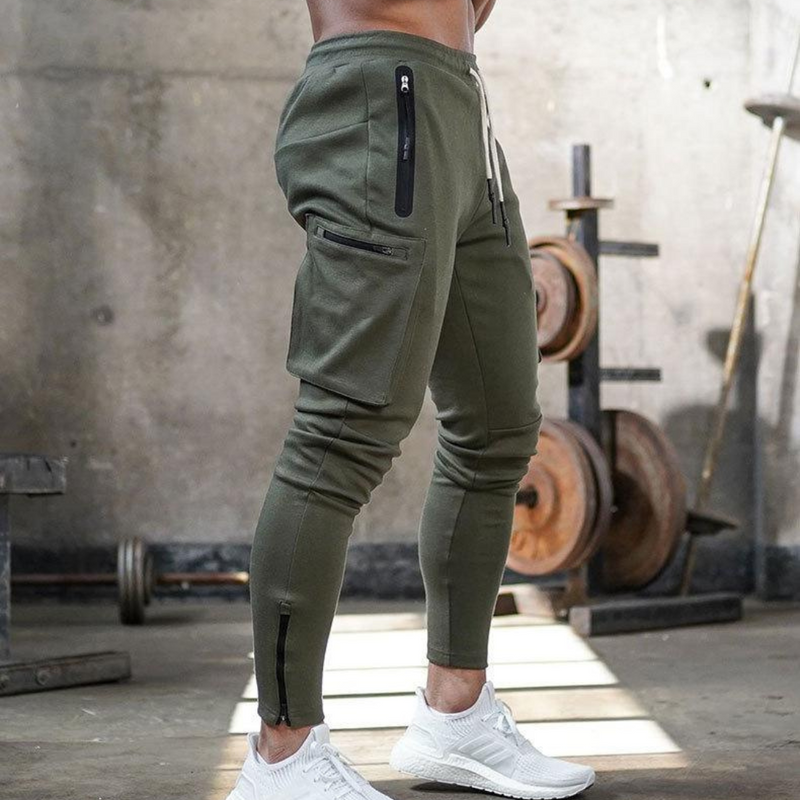 Laden Sie das Bild in Galerie -Viewer, Mann in olivgrüner Jogginghose mit Taschen, trainiert im Fitnessstudio. Sportbekleidung, Fitnessmode, Herrenleggings, Workout-Outfit.
