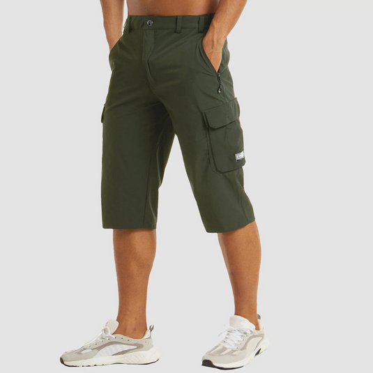 Grüne Cargo-Bermudashorts für Herren, knielang, mit Seitentaschen und Reißverschluss, kombiniert mit weißen Sneakers. Ideal für Freizeitmode.