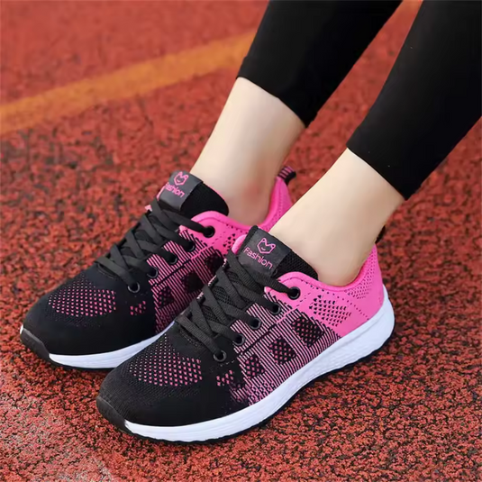 Damen-Laufschuhe in Schwarz und Pink auf rotem Asphalt. Bequeme Sportschuhe, ideal für Jogging und Fitness. Trendige Sneaker für Frauen.